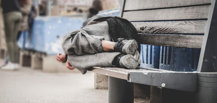homeless man asleep on bench