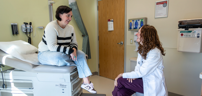 Val Beck chats from the edge of the exam table with Lindsey Davis, MD, her oncologist