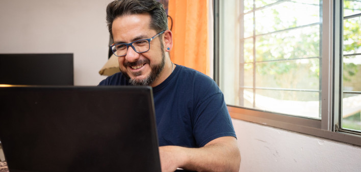 Latino man living with HIV using a laptop