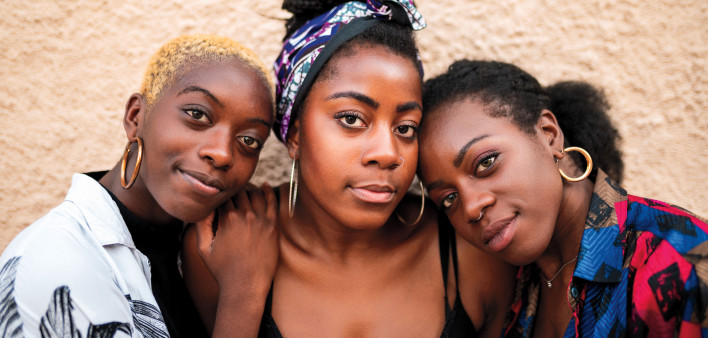 Three smiling black women hugging