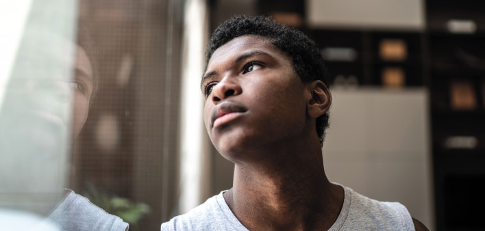 young black man looking at window