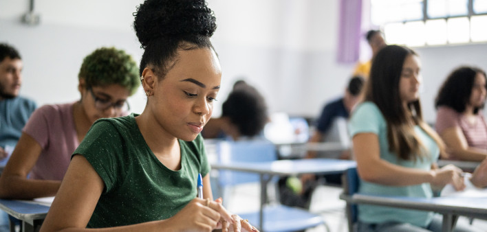 Teenage student writing in the classroom