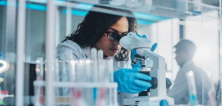 Medical Science Laboratory: Portrait of Beautiful Black Scientist Looking Under Microscope