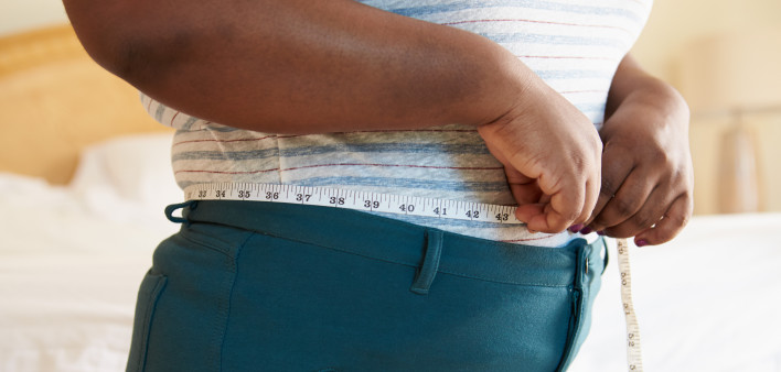 Close Up Of Overweight Woman Measuring Waist At Home Standing Still