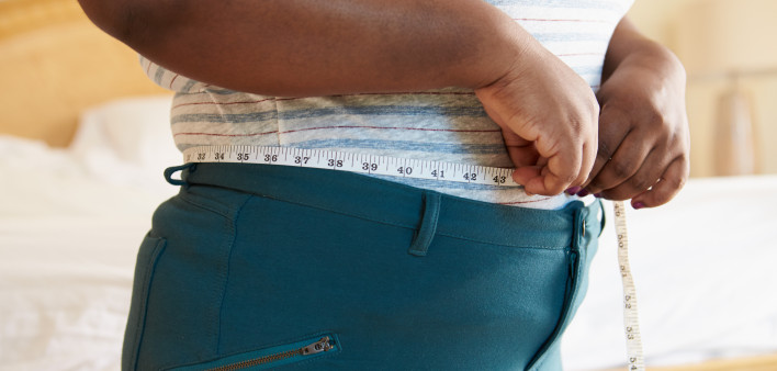 Close Up Of Overweight Woman Measuring Waist At Home Standing Still