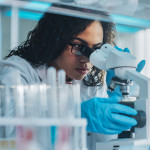 Medical Science Laboratory: Portrait of Beautiful Black Scientist Looking Under Microscope
