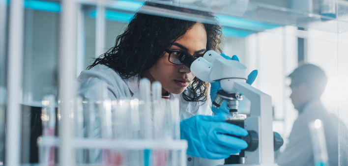 Medical Science Laboratory: Portrait of Beautiful Black Scientist Looking Under Microscope