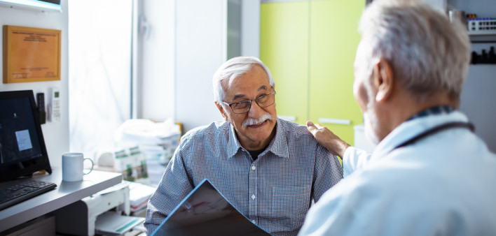 Doctor with x-rays and smiling old man patient