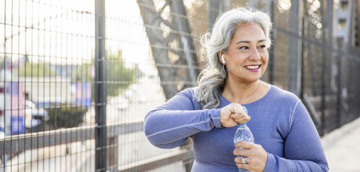 A senior Mexican woman drinking water after a workout