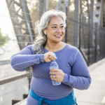 A senior Mexican woman drinking water after a workout