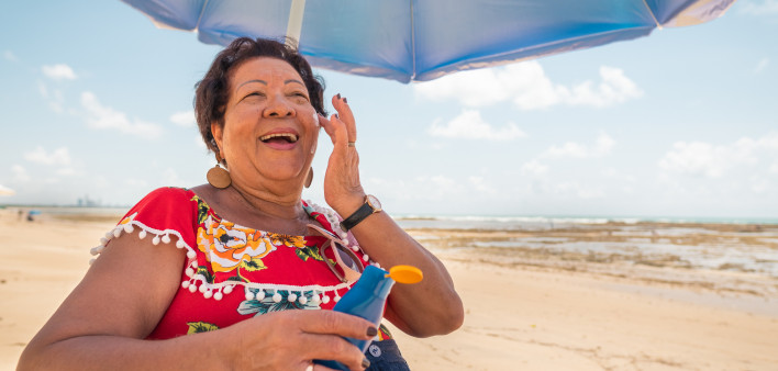 Senior woman using a suntan lotion on the beach