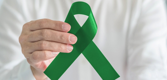 hand with green ribbon cerebral palsy and liver cancer awareness