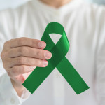 hand with green ribbon cerebral palsy and liver cancer awareness