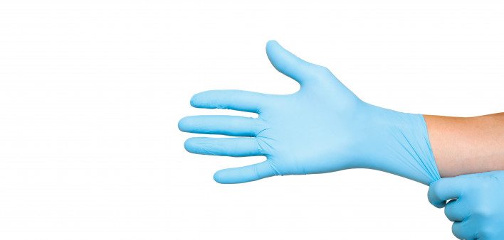 Doctor putting on protective blue gloves