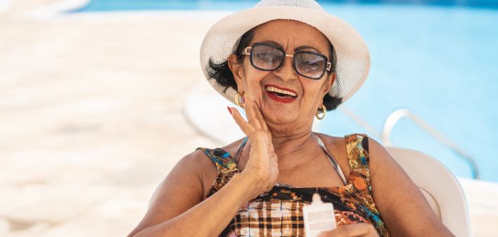 Mature woman applying suntan lotion sunscreen beach
