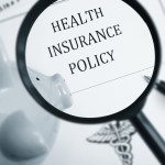 A maginfying glass looking at the words "Health Insurance Policy"