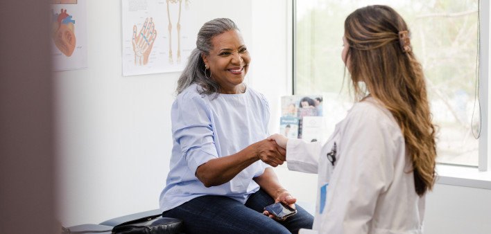 Unrecognizable doctor shakes hands with senior female patient stock photo
