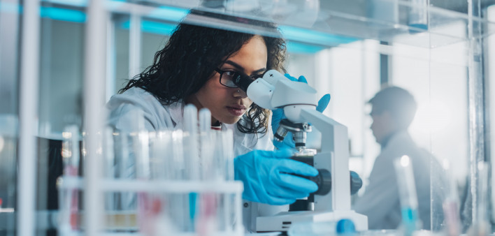 Medical Science Laboratory: Portrait of Beautiful Black Scientist Looking Under Microscope