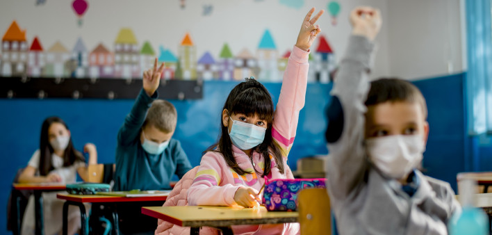 Elementary schoolchildren wearing a protective face masks in the classroom. Education during epidemic.