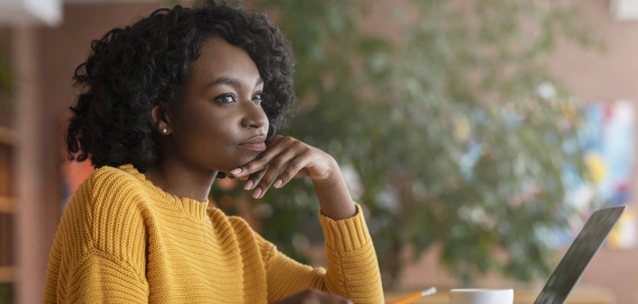 Thoughtful afro woman looking for new job online