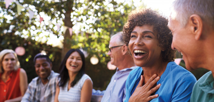 a group of adults sitting in the park laughing