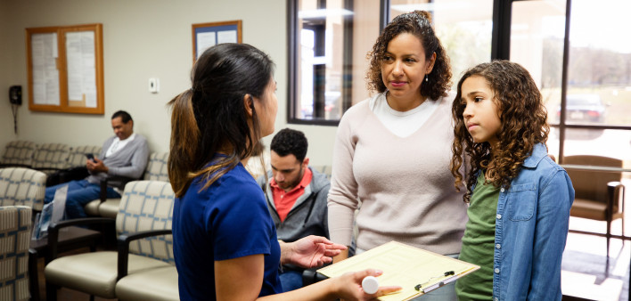 Young Latina girl and mother listen to nurse