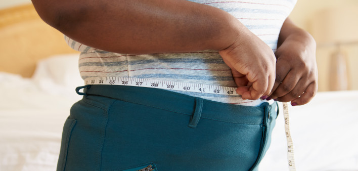 Close Up Of Overweight Woman Measuring Waist At Home Standing Still