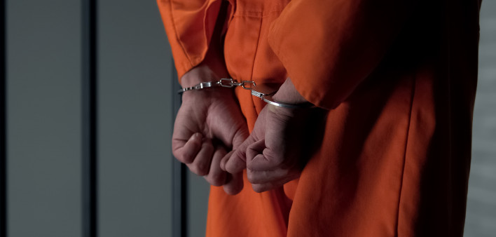 Prisoner with handcuffed arms behind back, another jail transfer, criminal