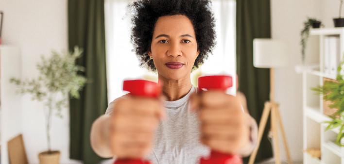 woman holding up red dumb bells
