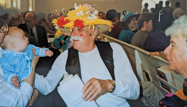 An MCC parishioner wearing an Easter bonnet greets a baby during the service