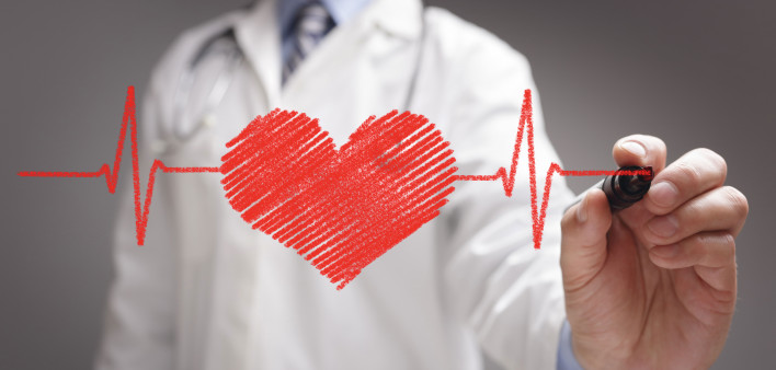 doctor in white coat drawing a red heart on glass