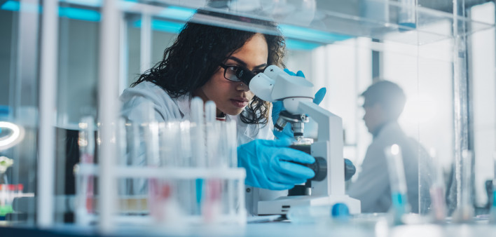 Medical Science Laboratory: Portrait of Beautiful Black Scientist Looking Under Microscope