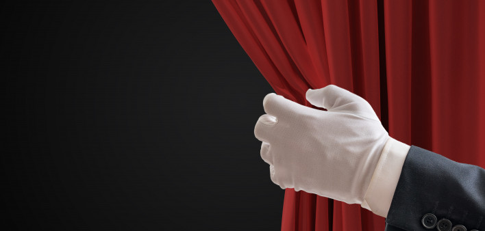 Actor is pulling red curtains in theatre with hand. white glove