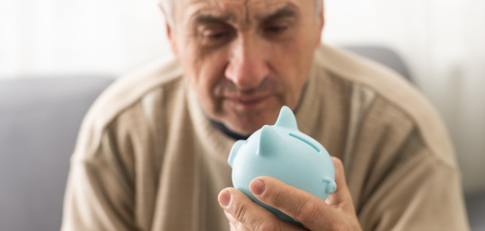 Senior caucasian man holding piggy bank with glasses depressed and worry for distress, crying angry and afraid.