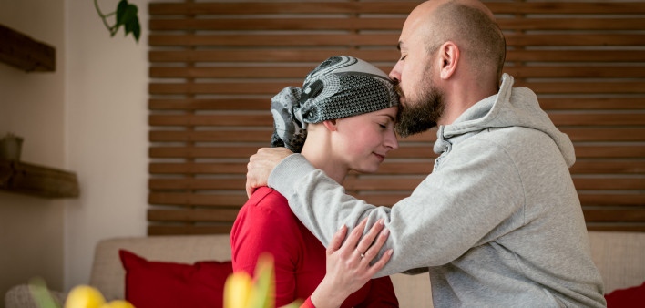 Supportive husband kissing his wife, cancer patient, after treatment in hospital.