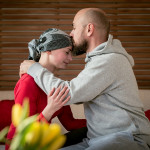 Supportive husband kissing his wife, cancer patient, after treatment in hospital.