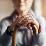 old woman, her hands resting on a cane