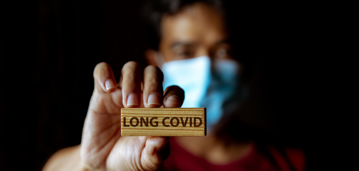Masked Asian man show wooden sign with wording "Long Covid"