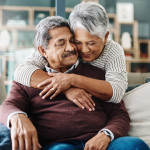 Cropped shot of a cheerful elderly woman hugging her husband who's in a wheelchair at home during the day