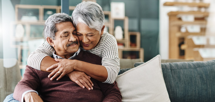 Cropped shot of a cheerful elderly woman hugging her husband who's in a wheelchair at home during the day