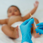 Doctor holding syringe and preparing vaccine giving injection to baby