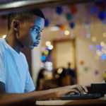 African american boy using a computer at night