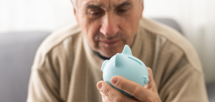 Senior caucasian man holding piggy bank with glasses depressed and worry for distress, crying angry and afraid.