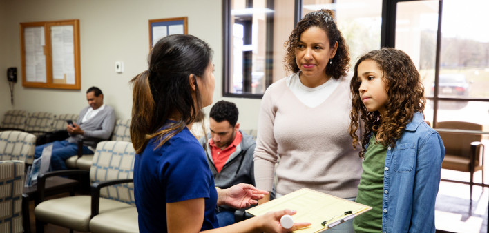 Young Latina girl and mother listen to nurse