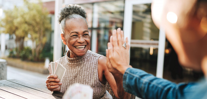 smiling black woman playing cards and high five with another player