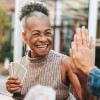 smiling black woman playing cards and high five with another player