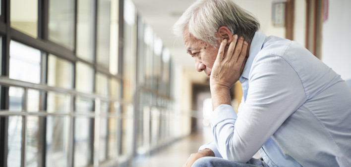 senior asian patient sitting in hospital hallway looking sad and depressed