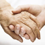 one hand holds the other elderly hand