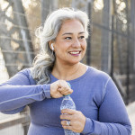 A senior Mexican woman drinking water after a workout