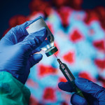 gloved hand needle vial vaccine coronavirus